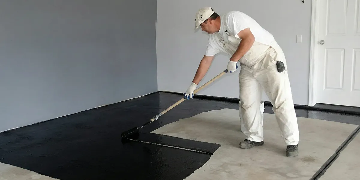 basement waterproofing professional applying waterproof coating to protect a basement floor in Milwaukee, WI